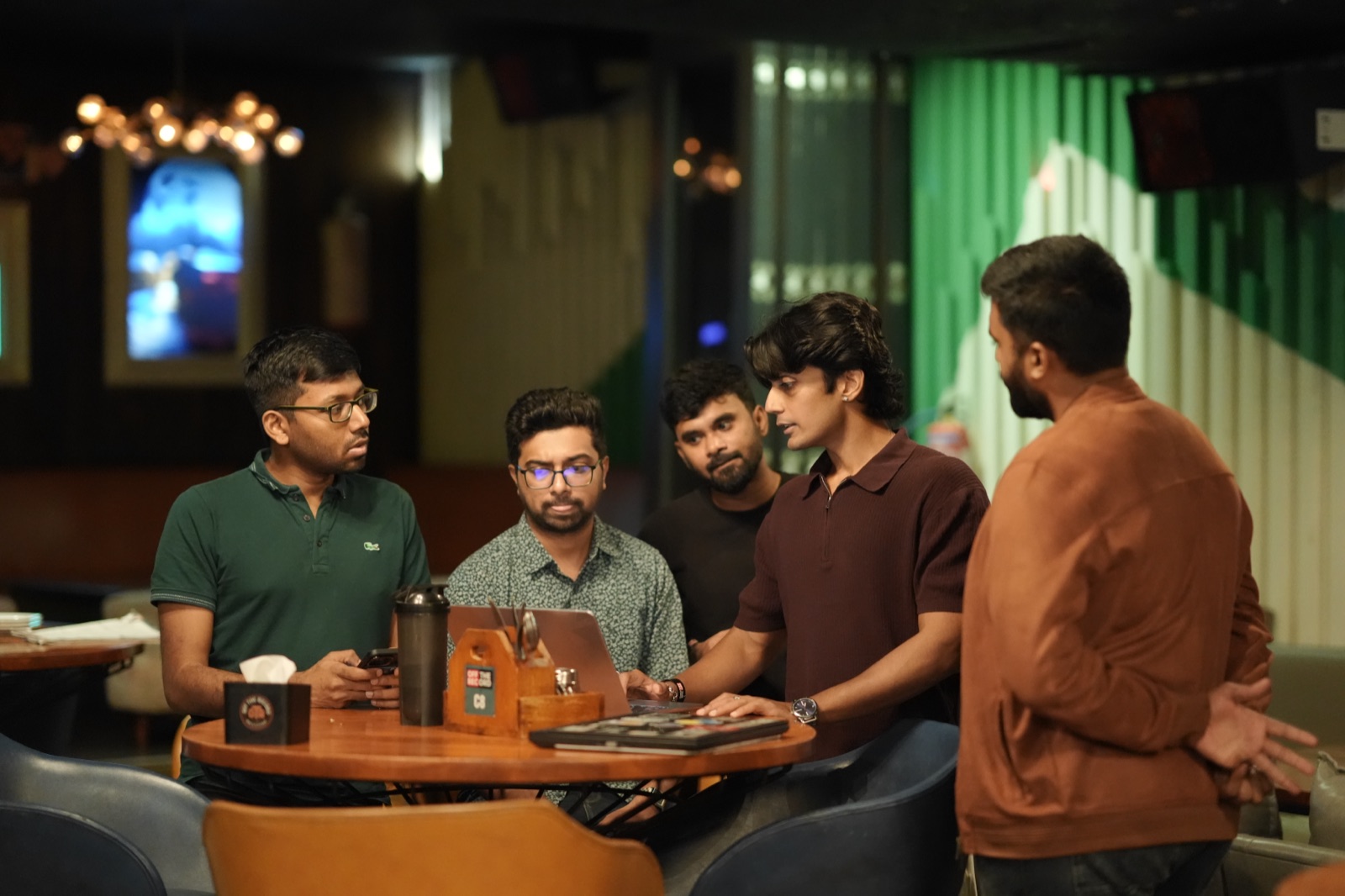 Five members collaborating around a table with a laptop at a Chennai meetup.